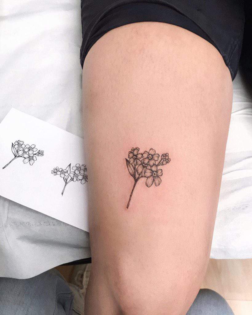 An elegant outline tattoo of forget-me-not flowers on the thigh, capturing simplicity and symbolism with its minimalist design