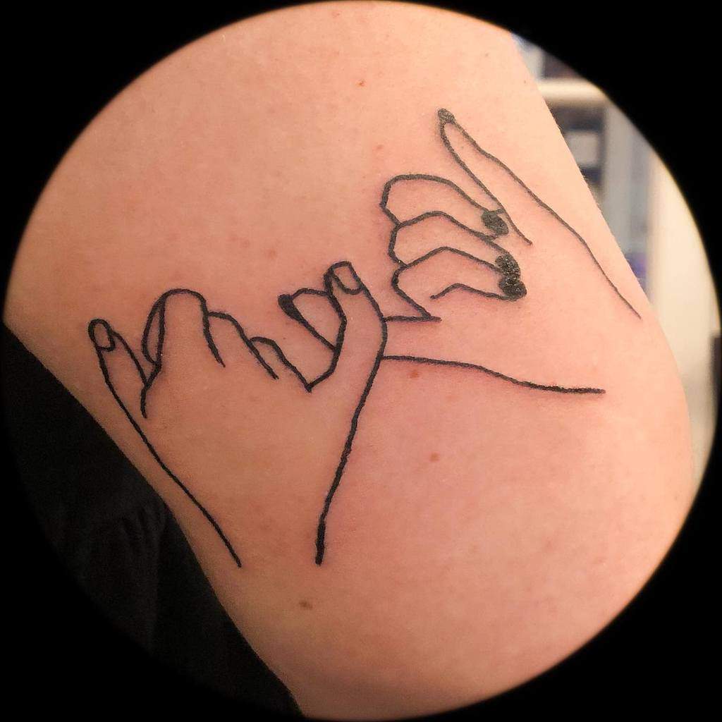 Line art tattoo of two hands making a pinky promise on an arm