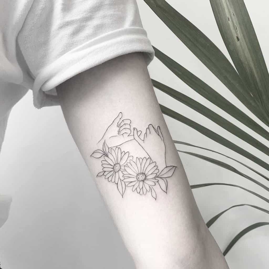 A minimalist tattoo on an arm features two hands making a pinky promise