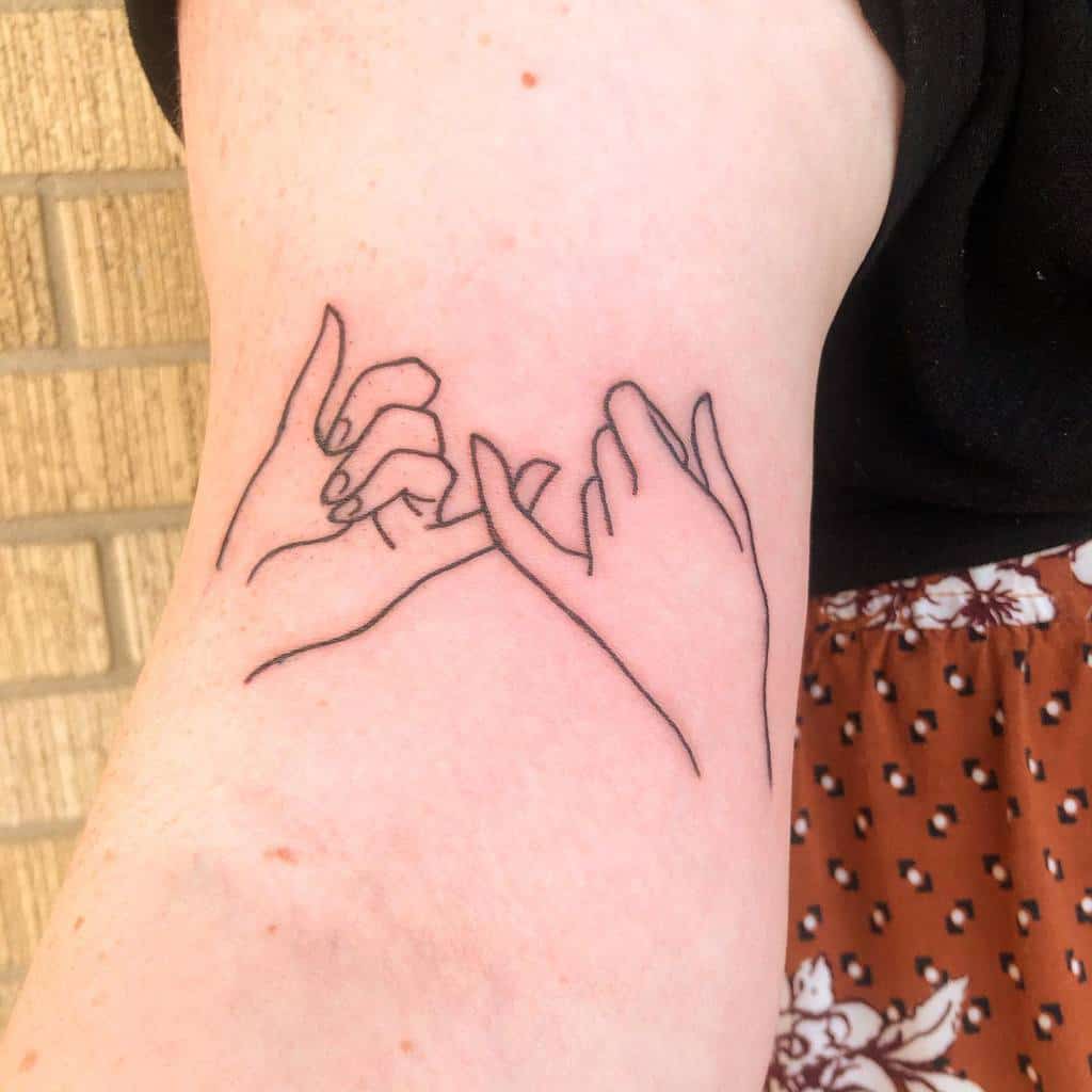Line art tattoo of two hands making a pinky promise on an arm
