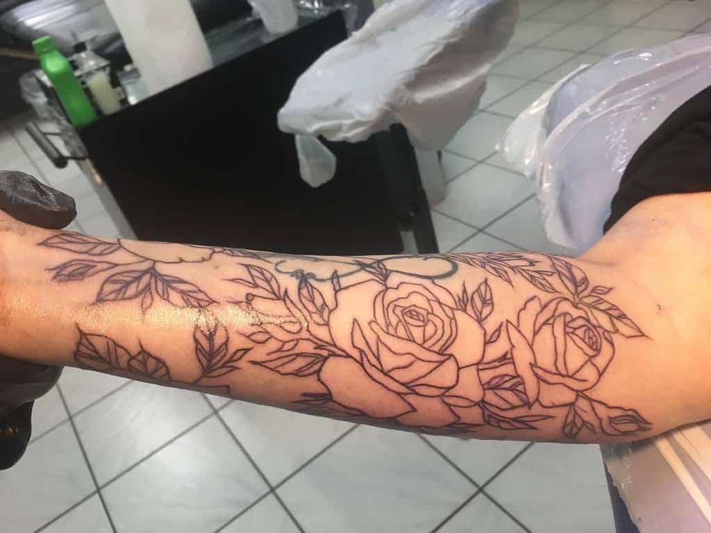 Forearm tattoo featuring outlined roses and leaves