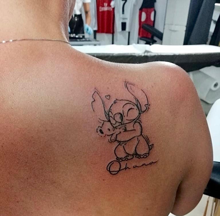 Minimalist tattoo of Stitch hugging Scrump with 'Ohana' written below, symbolizing love, family, and loyalty.