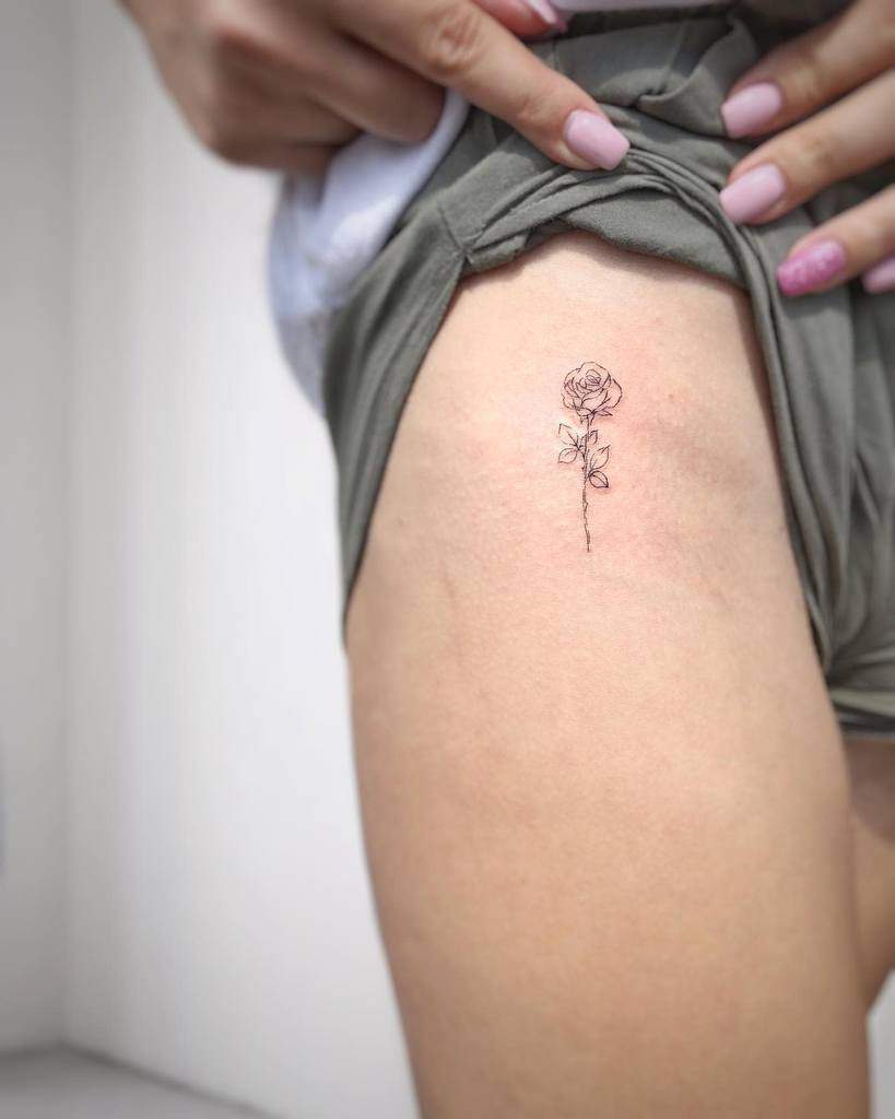 A small rose tattoo on a woman's upper thigh
