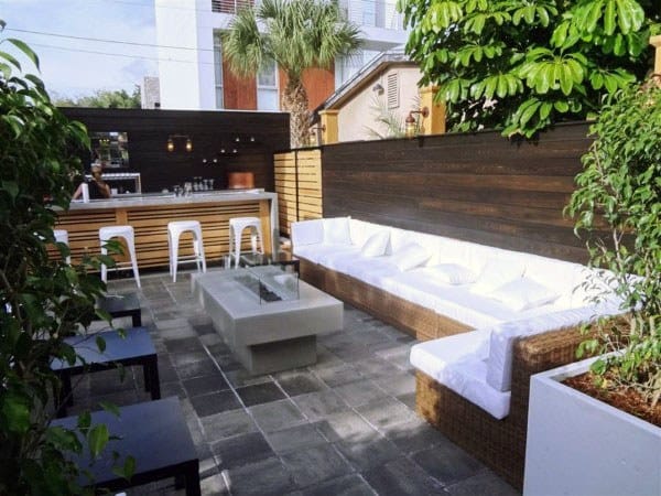 Modern wood pallet bar with white barstools, sectional seating, and sleek outdoor decor.