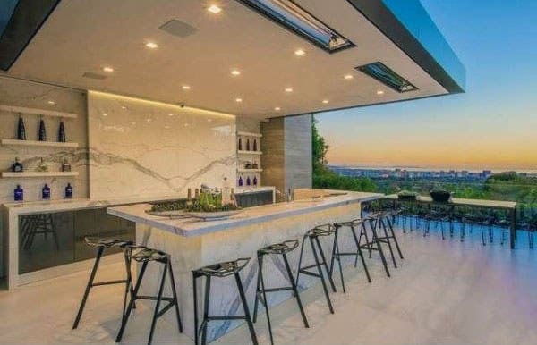 Outdoor bistro bar with marble island, sleek bar stools, and panoramic views at sunset.