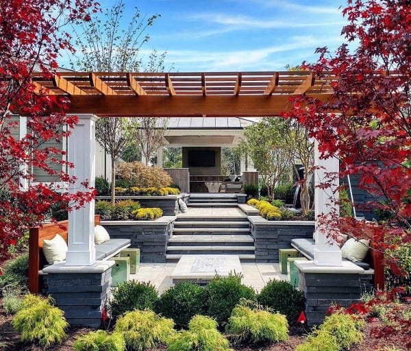 Patio garden with a wooden pergola, red trees, cozy seating, and steps to an inviting outdoor lounge