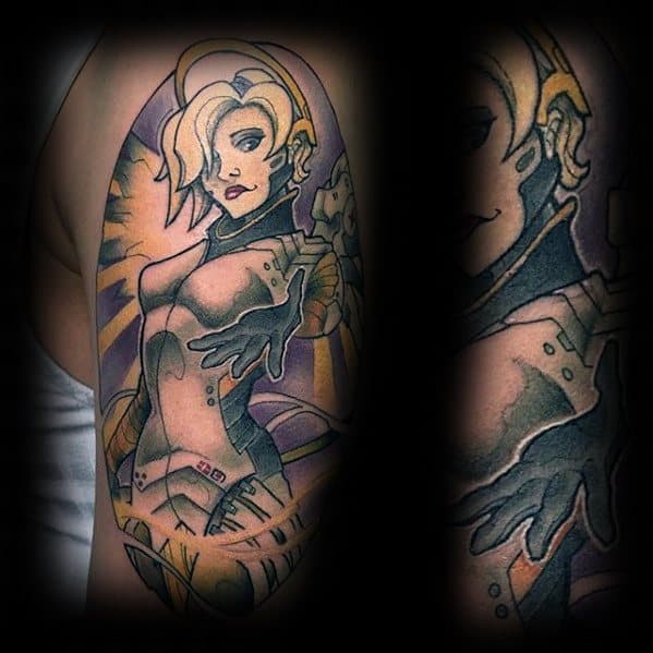 Vibrant upper arm tattoo of Mercy from Overwatch, depicted in a dynamic pose with glowing wings and soft purple-yellow shading.