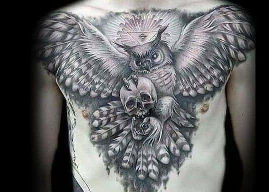 A detailed chest tattoo of an owl with a skull in its talons