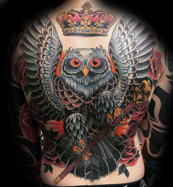A detailed back tattoo of an owl with a crown and scepter, surrounded by roses