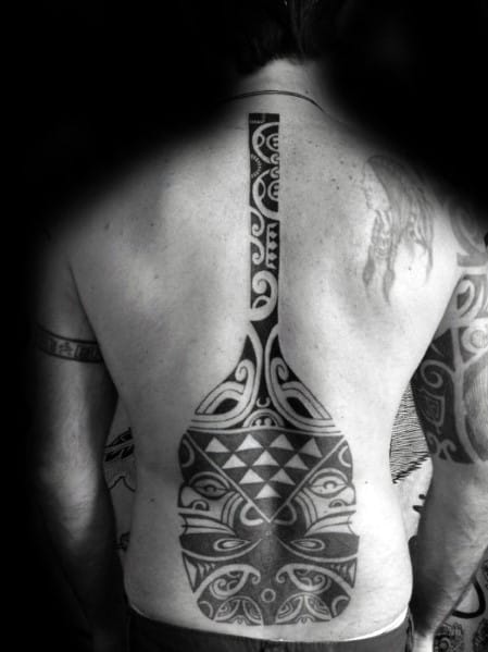 Large tribal-style paddle tattoo covering the back, featuring intricate Polynesian patterns, symbolizing strength, heritage, and a deep connection to water.