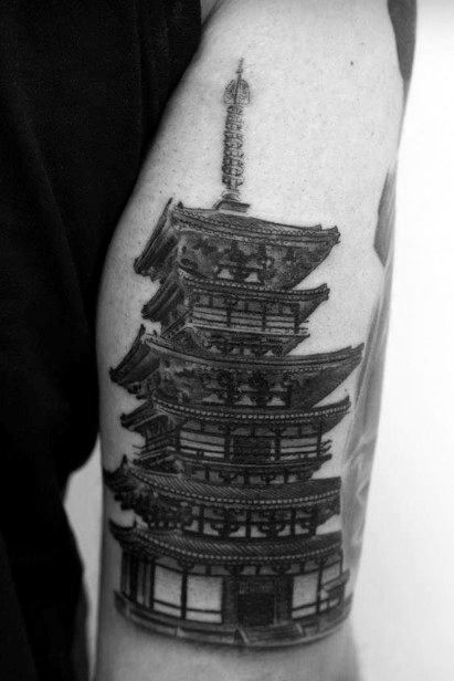 Detailed black and grey upper arm tattoo of a traditional five-tiered Japanese pagoda with fine architectural linework.