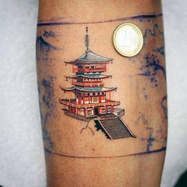 Small, detailed tattoo of a red Japanese pagoda with stairs and minimal background, placed on the arm and sized next to a coin.