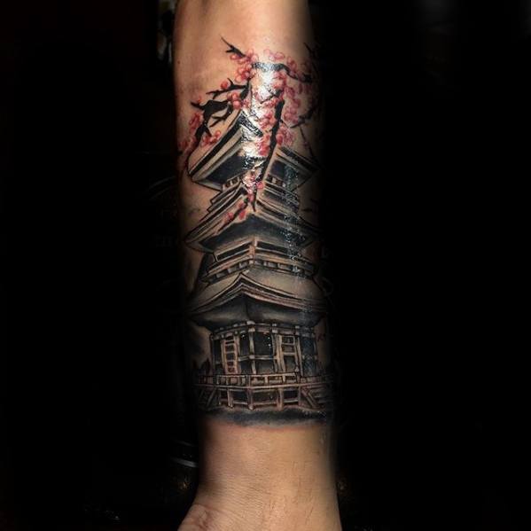 Forearm tattoo of a Japanese pagoda in black and grey with red cherry blossoms and dramatic shading for a bold, artistic contrast.