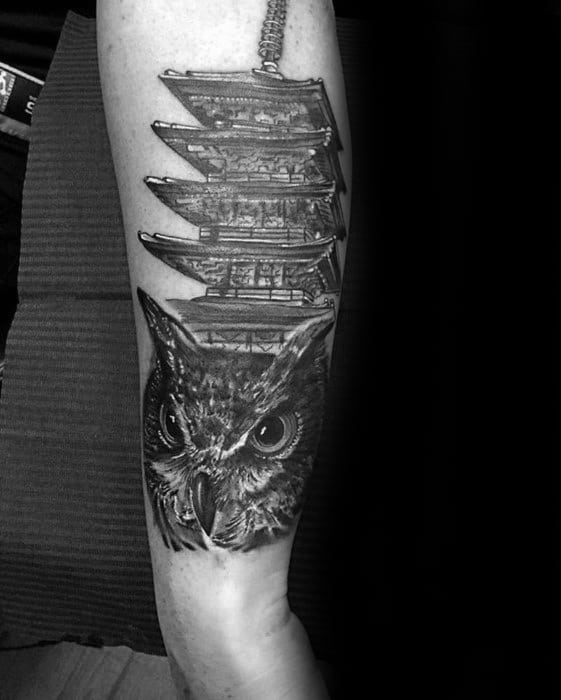 Black and grey forearm tattoo of a Japanese pagoda above a realistic owl head, blending wisdom and tradition in a bold vertical design.
