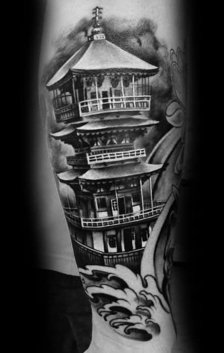Black and grey tattoo of a traditional Japanese pagoda with detailed railings and rooftops, set above stylized crashing ocean waves.