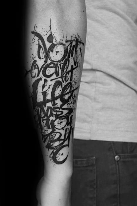 Forearm tattoo with the words "Don't accept life as it is" in artistic black font