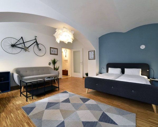 Spacious studio with blue accent wall, bike decor, modern furniture, and geometric rug.