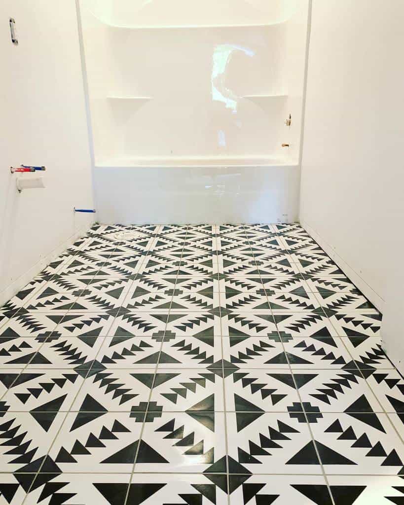 Basement bathroom with bold black and white geometric tile flooring and a white bathtub setup.