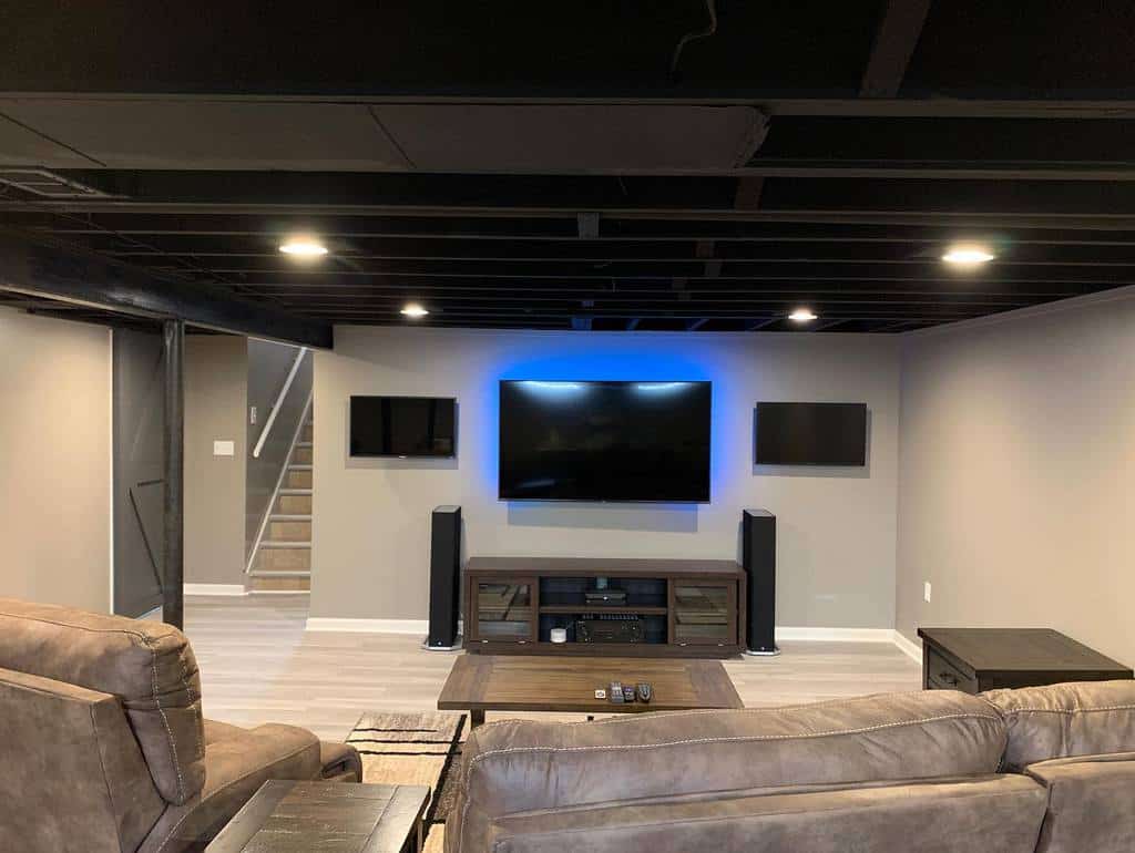 Basement lounge room with mounted TV, neutral walls, and cozy brown recliner seating.