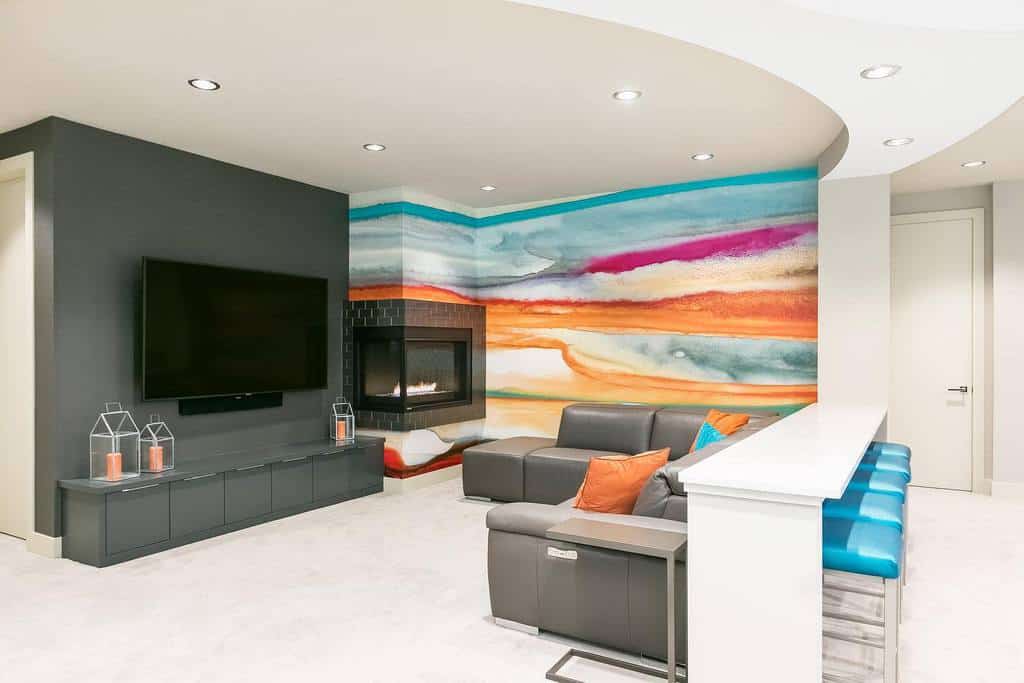 Basement living space with a vibrant multicolored accent wall, fireplace, and modern seating arrangement.