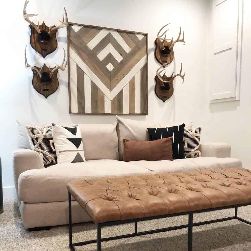 Modern lounge with beige sofa, leather ottoman, and rustic deer head wall decor.