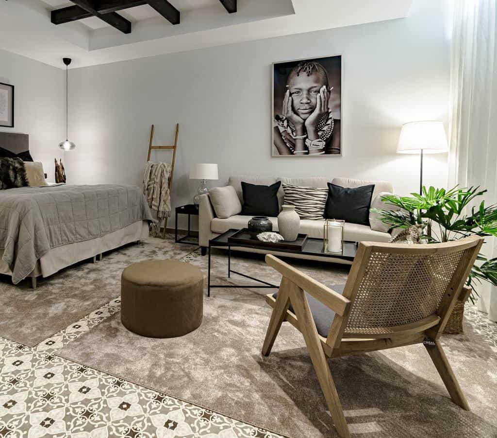 Modern bedroom with cozy seating area, wooden chair, and portrait wall art.
