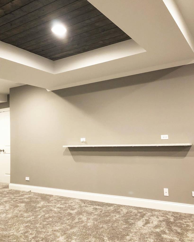 Empty room with grey walls, recessed ceiling, and a floating shelf.