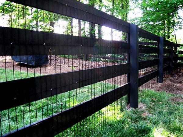 Black wooden fence with wire mesh, enclosing a shaded backyard area.