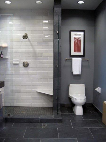 Bathroom featuring dark grey walls, white subway-tiled shower with glass doors, and slate flooring.