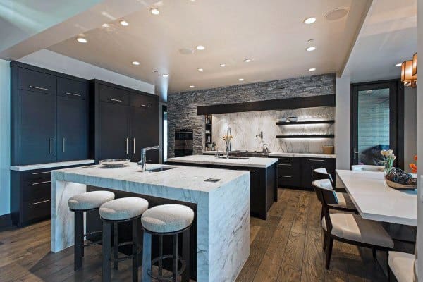 Modern kitchen with marble island, barstools, dark cabinets, wood flooring, and recessed lighting