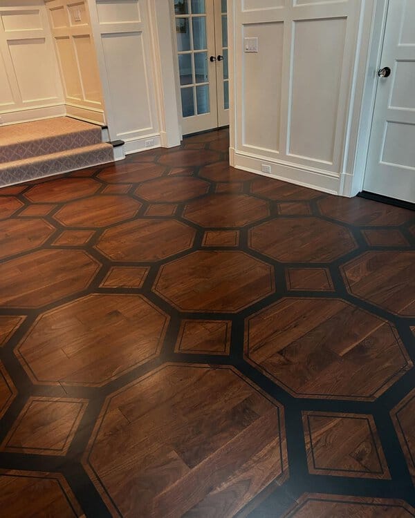 Dark wood floor with octagonal shapes outlined in black, surrounded by white paneled walls and French doors.