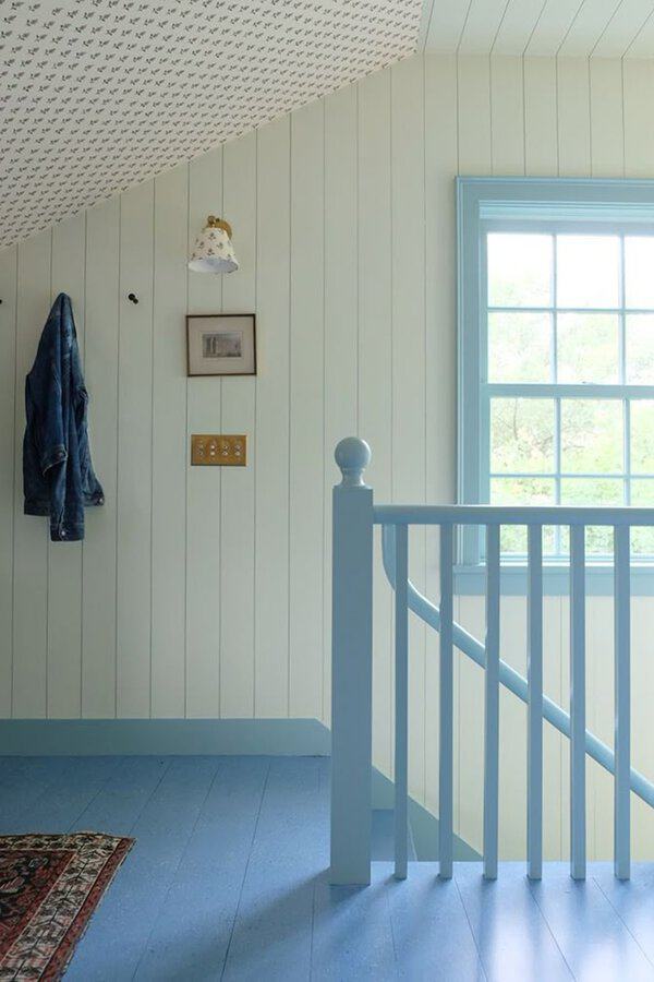 Landing with pale blue painted wood floor, white paneled walls, patterned ceiling, and matching window trim.