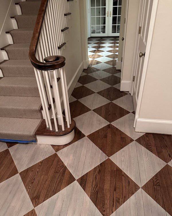Hallway with a diagonal checkerboard wood floor in alternating natural and whitewashed squares, leading to French doors.