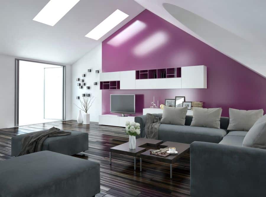 Modern living room with an accent wall in purple, gray sofas, and a sleek TV unit under skylights
