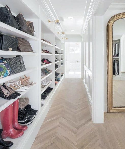 Organized walk-in closet with painted white crown molding, shelves for shoes and bags, and a full-length mirror, showcasing stylish storage