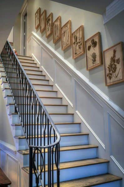 framed photos on wood staircase with metal railing