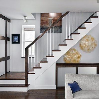 Modern staircase with dark wood steps, white risers, and metal railings in a stylish living room.