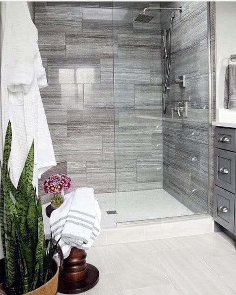 Grey travertine tile shower with glass enclosure and modern chrome fixtures.