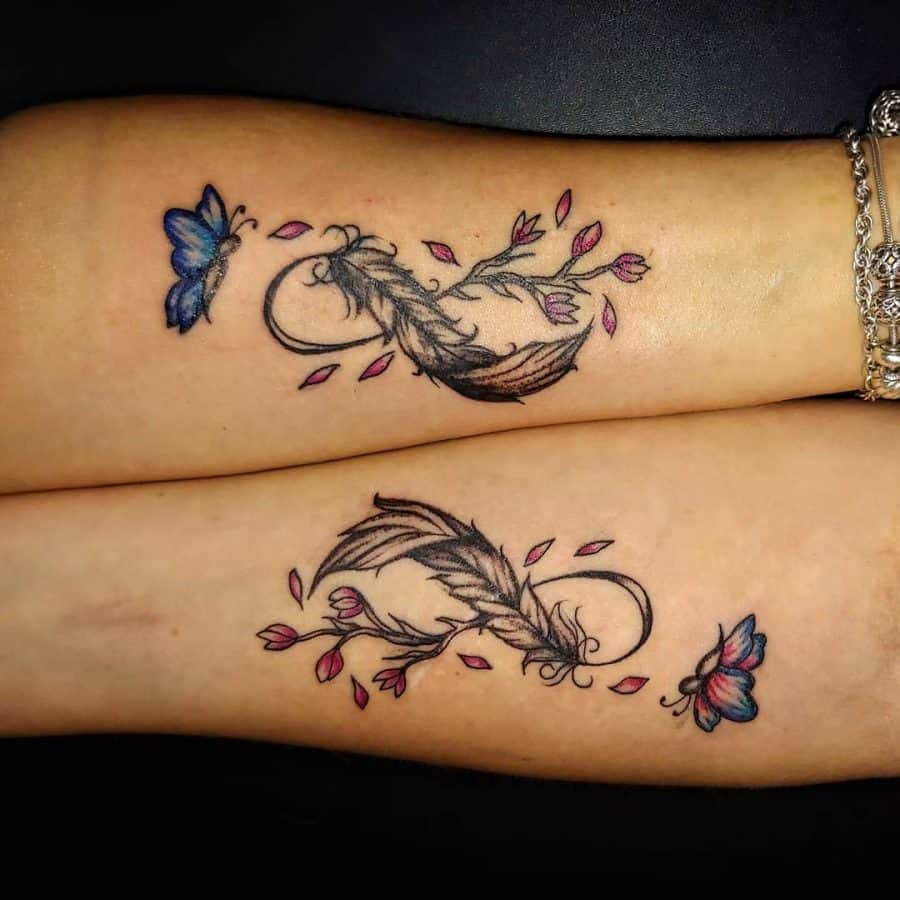 Matching tattoos of a feather and butterfly with pink petals on two forearms