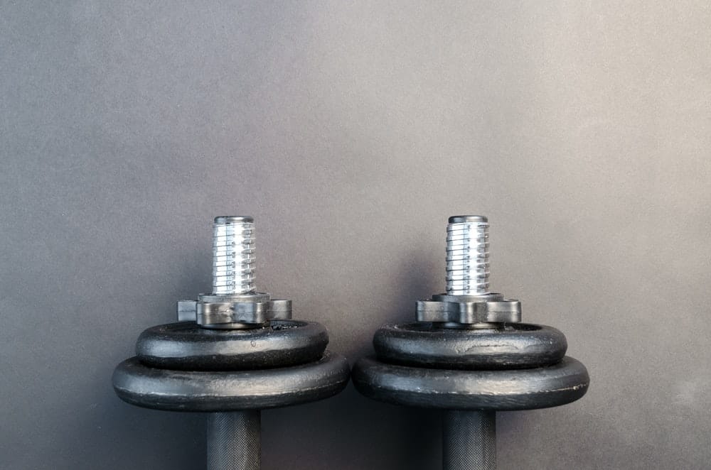 pair of two dumbbells sit on a black surface