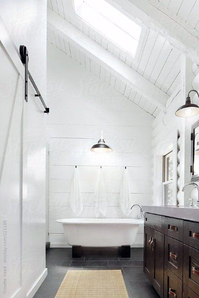 Modern bathroom with skylight, white walls, freestanding tub, and dark wood vanity