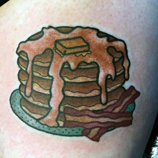 Stack of pancakes tattoo with dripping syrup, butter, and crispy bacon on a plate, featuring bold outlines and a classic diner-style design.