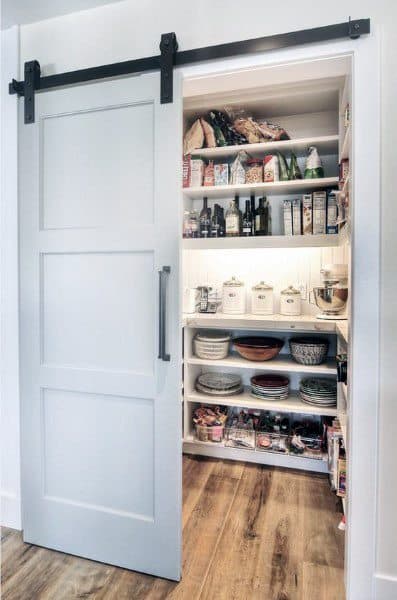 Farmhouse-style pantry with sliding barn door and neatly arranged shelves.