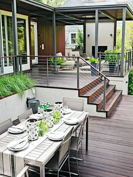 Multi-level wooden deck with cable railing, outdoor dining table, and built-in planters.
