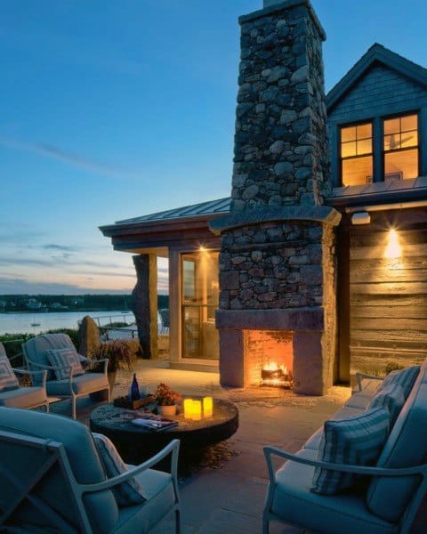 Cozy patio with a fireplace, candles, and a stunning view of the lake at sunset
