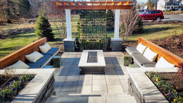 A patio with benches, a fire pit, and a pergola graces the landscaped yard