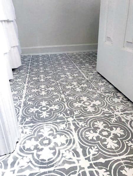 Room with decorative white and gray patterned tile flooring, resembling a concrete floor, and part of a white door