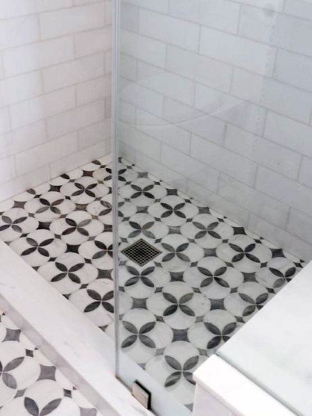 Shower with glass partition and geometric black and white floor tiles