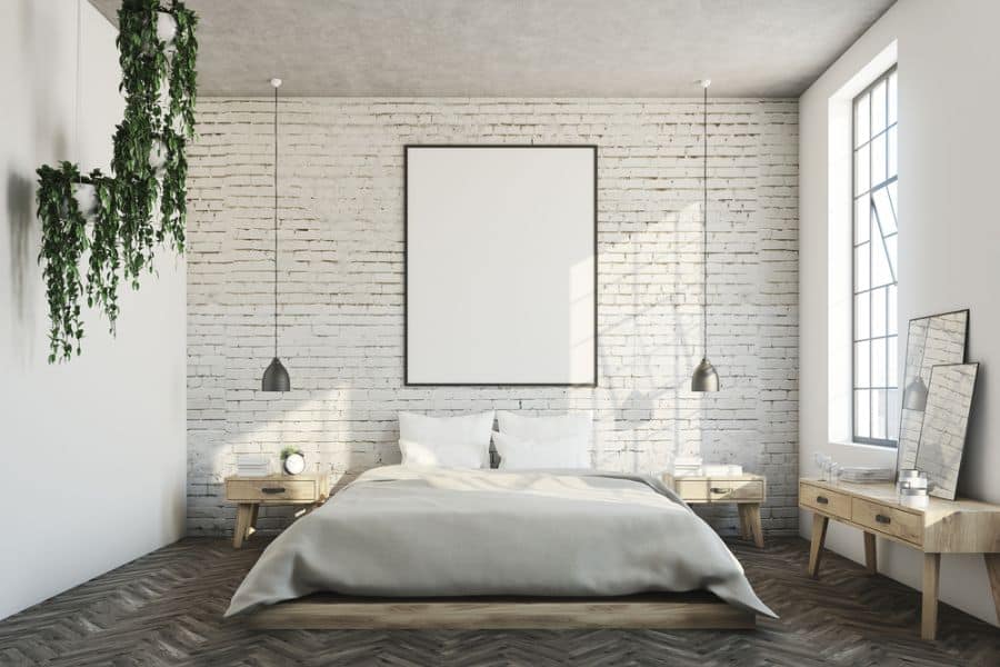 Modern minimalist bedroom featuring low-hanging lights, a white brick wall, and natural decor elements.