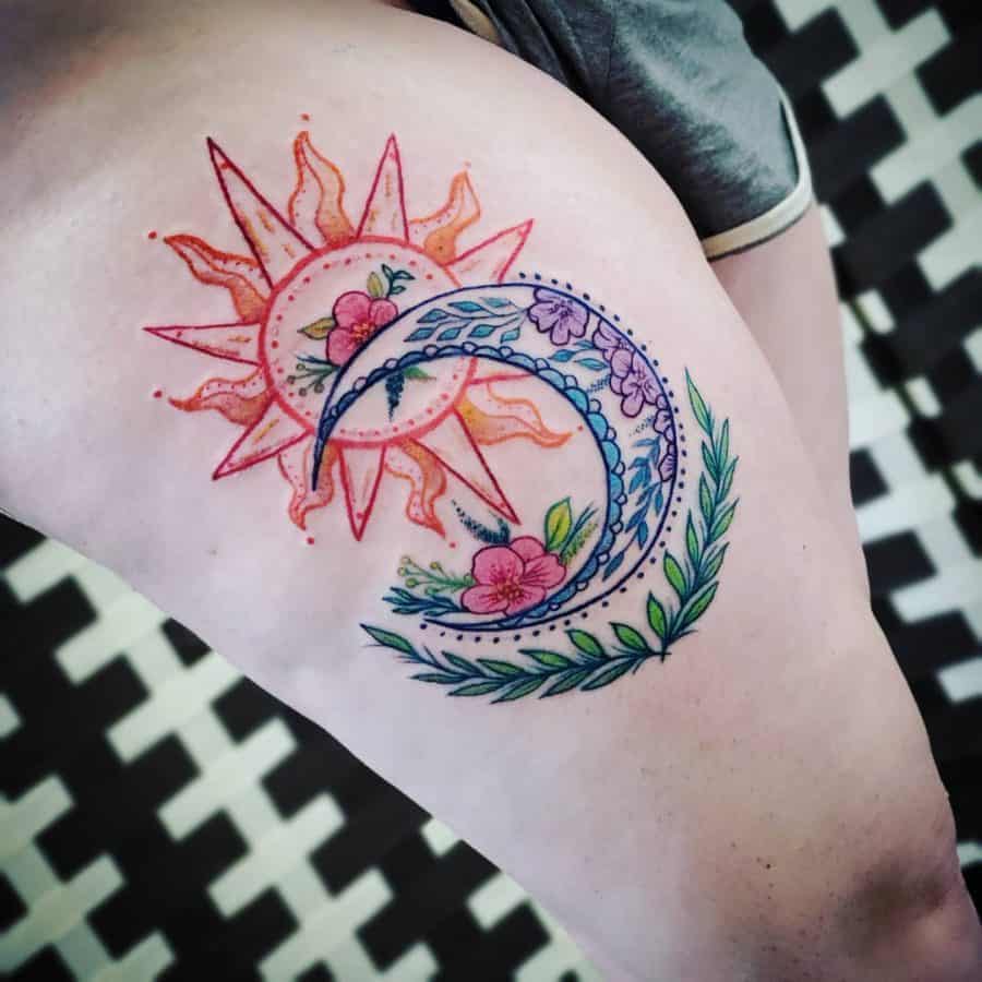 Colorful sun and moon tattoo with floral details, featuring a red-orange sun and a blue crescent moon adorned with flowers and leaves.